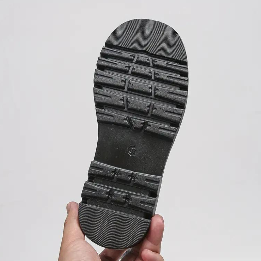 Zwarte rubberen schoenzool met antislipprofiel, vastgehouden door een hand. Ideaal voor stevige grip en duurzaamheid. Geschikt voor wandelschoenen.