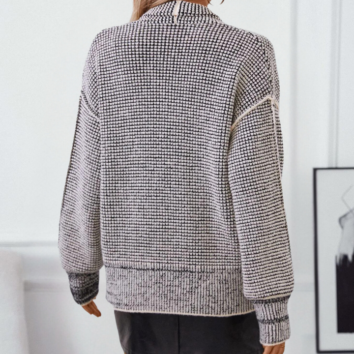 Damestrui met zwart-wit geruit patroon, lange mouwen en geribbelde boorden, perfect voor herfstmode. Comfortabele en stijlvolle gebreide kleding.