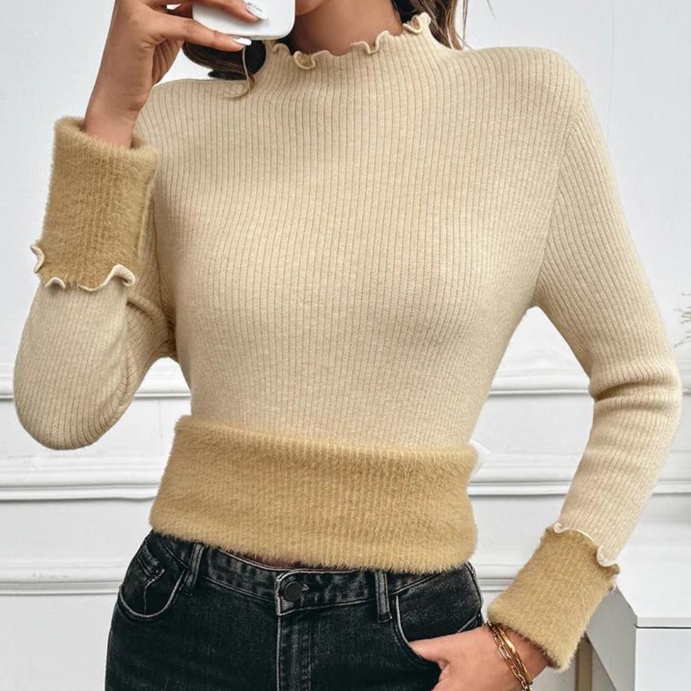Vrouw draagt beige geribbelde trui met ruches, gecombineerd met zwarte jeans. Modieuze dameskleding, herfststijl, casual outfit.