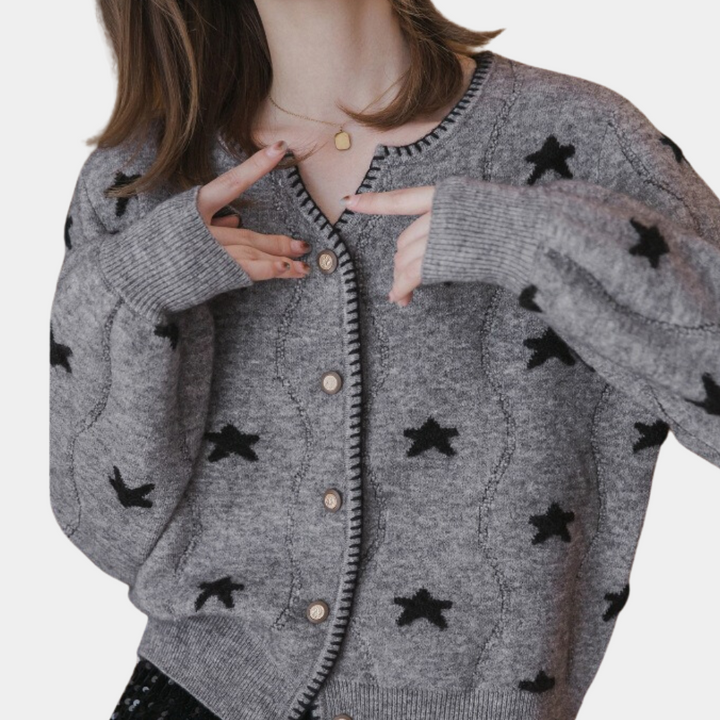 Grijze damestrui met zwarte sterpatronen en knopen, gedragen door model. Trendy gebreide kleding, herfstmode, comfortabele dameskleding.