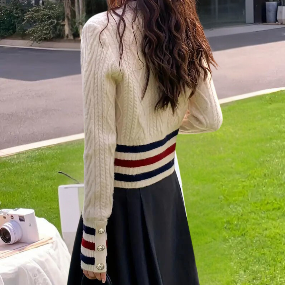 Vrouw in gebreide trui met strepen en knopen, buiten op grasveld. Modieuze dameskleding, herfststijl, casual outfit.