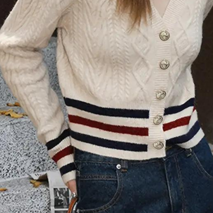 Beige kabeltrui met V-hals, gouden knopen en gestreepte boorden in rood, wit en blauw. Stijlvolle damesmode, herfstkleding, casual chic.