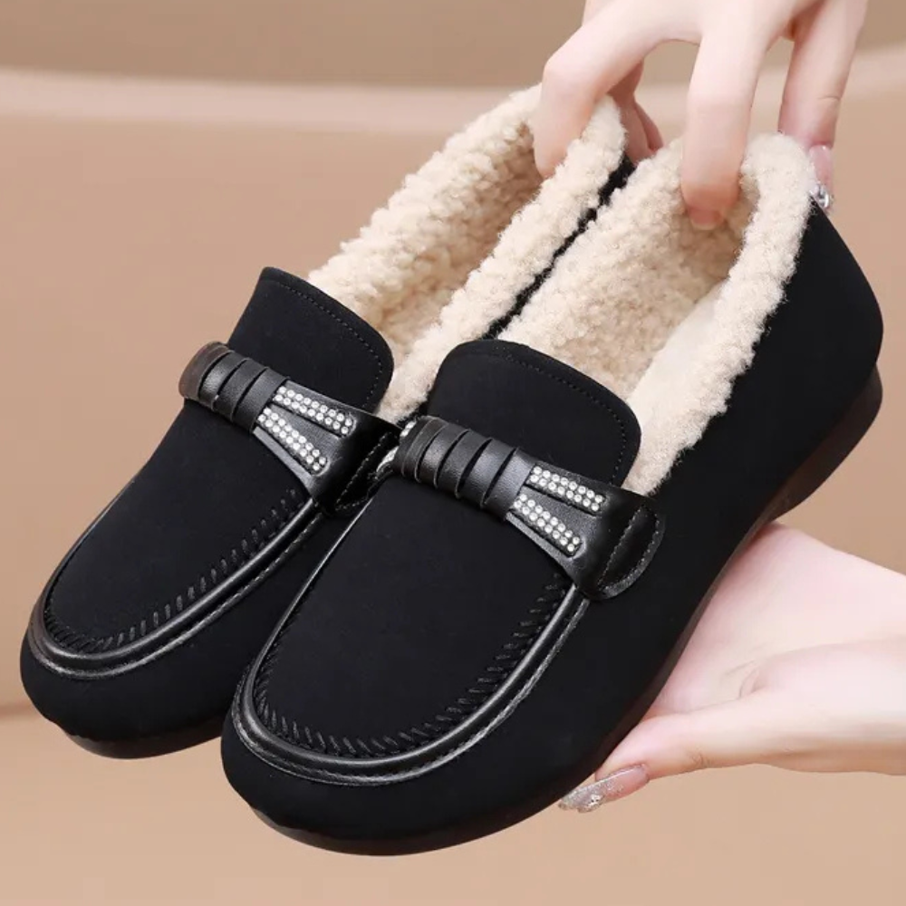 Zwarte dames instappers met bontvoering, decoratieve riem en stiksels. Comfortabele winter schoenen, ideaal voor dagelijks gebruik.