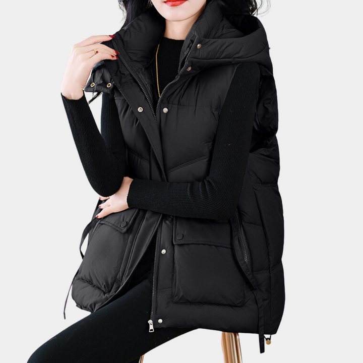 Vrouw in zwarte gewatteerde bodywarmer met capuchon, stijlvolle wintermode, comfortabele dameskleding, trendy en warm, casual outfit.