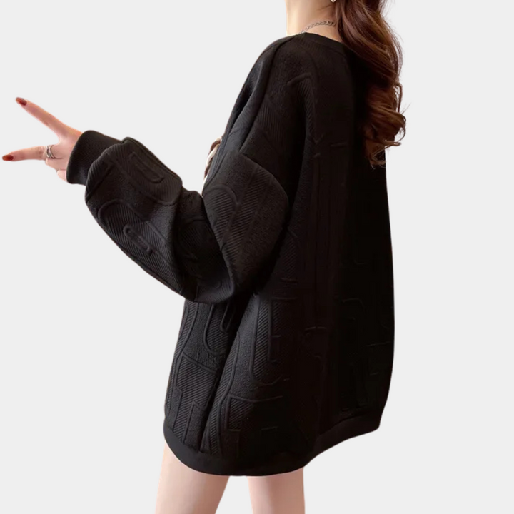 Zwarte oversized trui met textuur, gedragen door model. Modieuze dameskleding, comfortabele pasvorm, trendy design, perfect voor casual outfits.