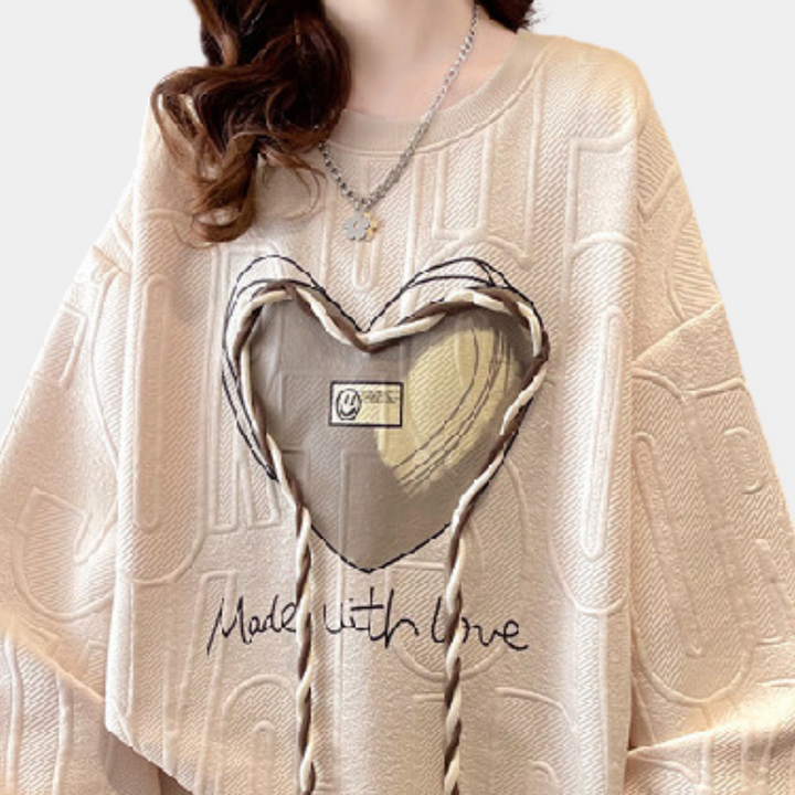 Beige trui met hartvormig detail en "Made with Love" tekst, damesmode, casual stijl, gebreid patroon, trendy kleding, kettingaccessoire.