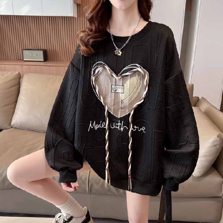 Zwarte oversized trui met hartvormige applicatie en "Made with Love" tekst, trendy damesmode, comfortabele casual outfit, herfstkleding.