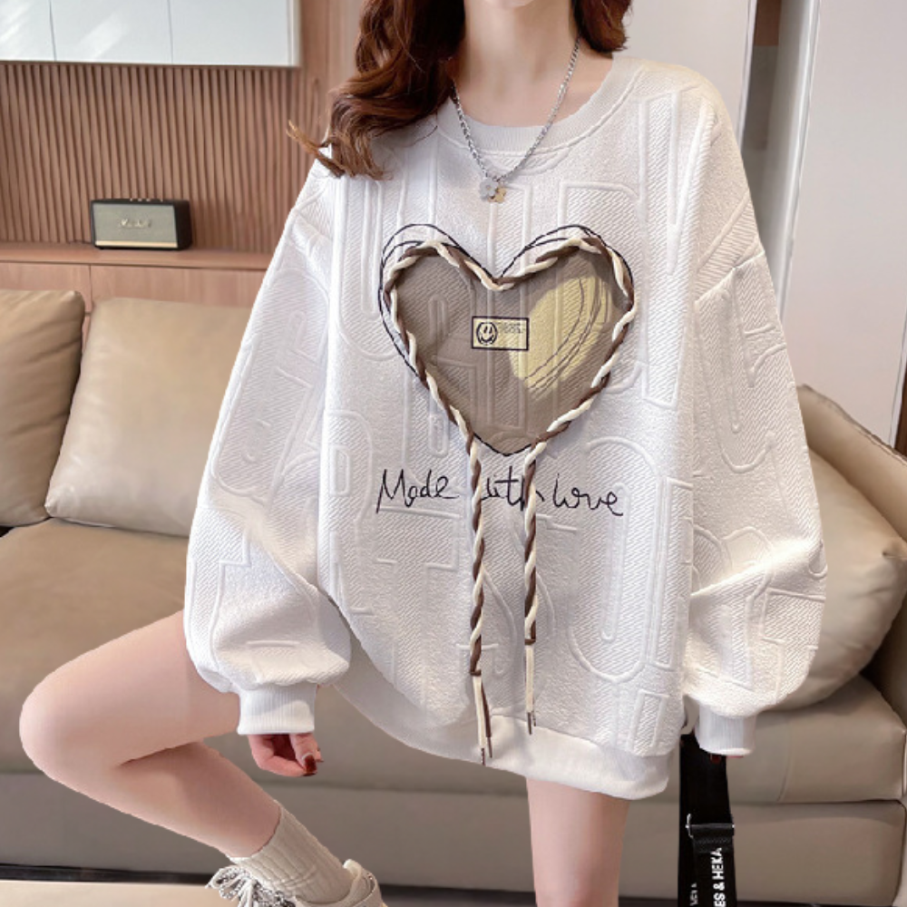 Witte oversized trui met hartvormig patroon en tekst "Made with Love", trendy damesmode, comfortabele casual outfit, perfect voor herfst en winter.