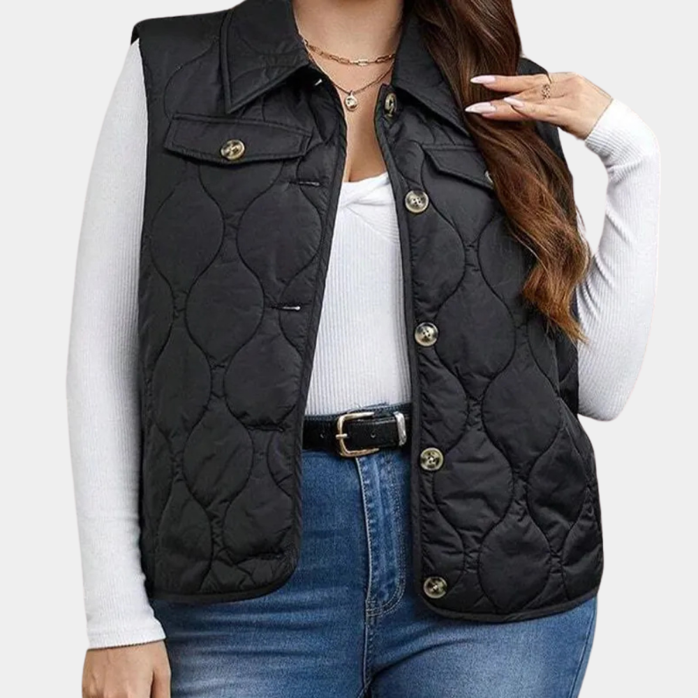 Dames zwarte gewatteerde bodywarmer, knoopsluiting, gedragen over witte trui en jeans. Modieuze herfstkleding, casual stijl.