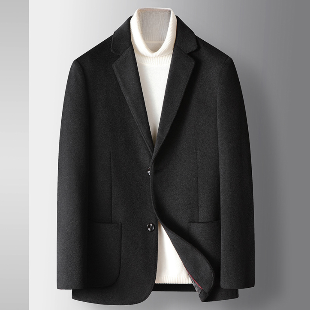 Zwarte herenblazer met klassieke revers, twee knopen en opgestikte zakken, gedragen over een witte coltrui. Stijlvolle zakelijke kleding.
