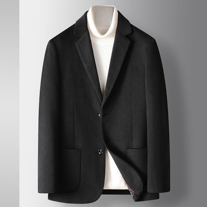 Zwarte herenblazer met klassieke revers, twee knopen en opgestikte zakken, gedragen over een witte coltrui. Stijlvolle zakelijke kleding.