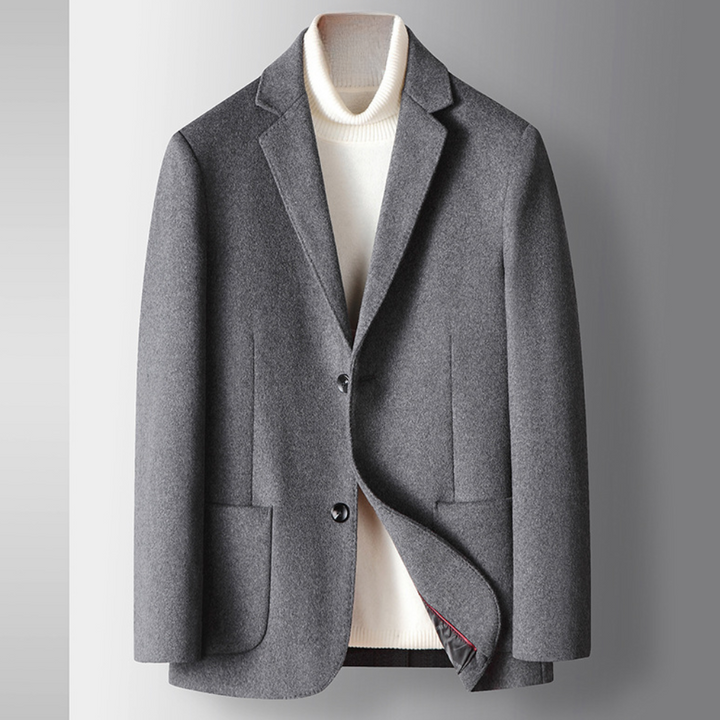 Grijze wollen blazer voor heren, klassieke stijl, met twee knopen en opgestoken revers, over een witte coltrui. Perfect voor zakelijke gelegenheden.
