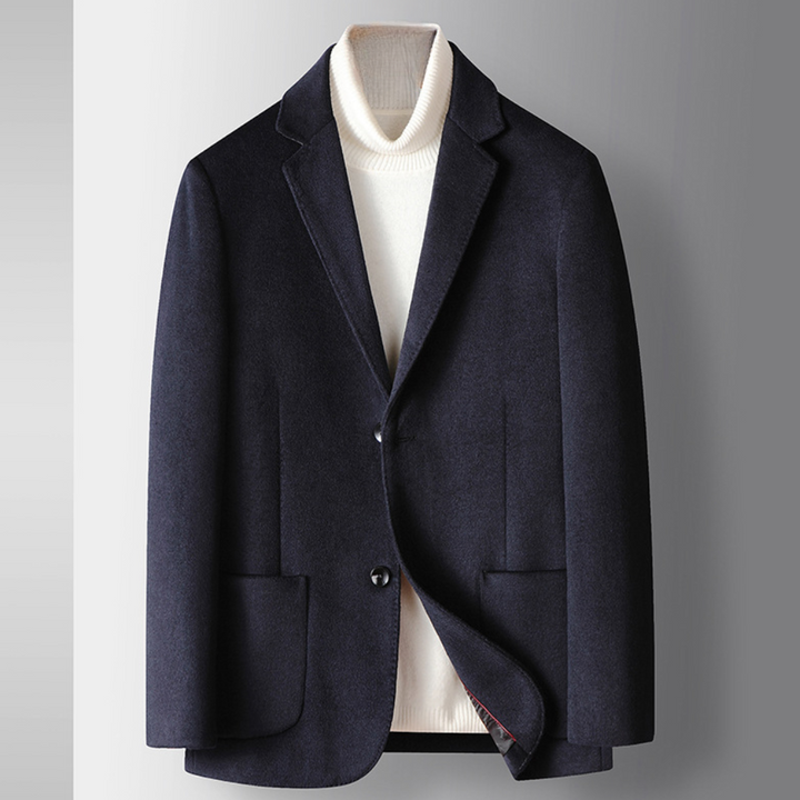 Donkerblauw herenjasje met revers, twee knopen en opgestikte zakken, gedragen over een witte coltrui. Stijlvolle zakelijke kleding.