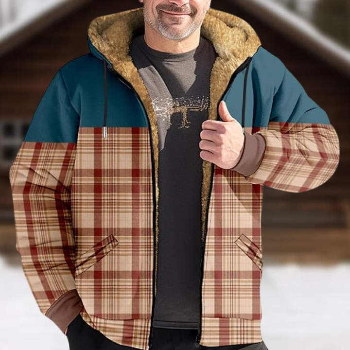 Man in geruite winterjas met capuchon voor houten chalet. Warme, stijlvolle jas met blauwe en bruine tinten, ideaal voor koude weersomstandigheden.