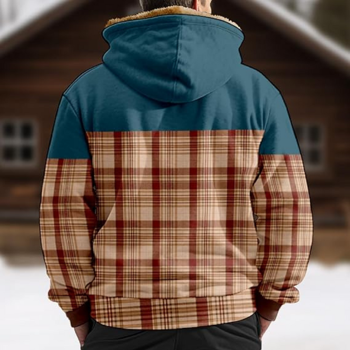 Achterkant van een geruite herenhoodie met blauwe capuchon, gedragen voor een houten huis. Wintermode, casual kleding, warme jas.