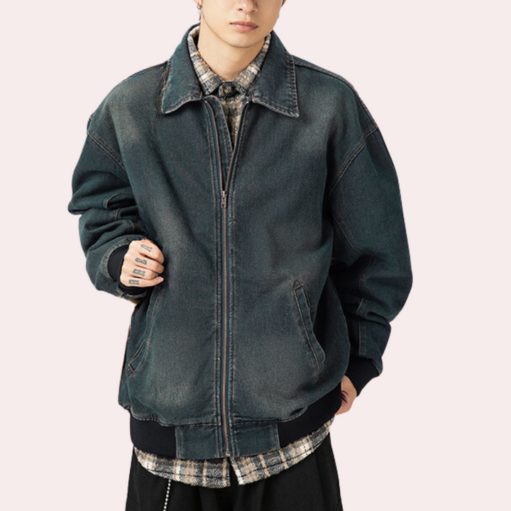 Donkerblauwe oversized spijkerjas voor heren, gedragen over geruite blouse. Modieuze streetwear, casual stijl, ideaal voor herfst en winter.