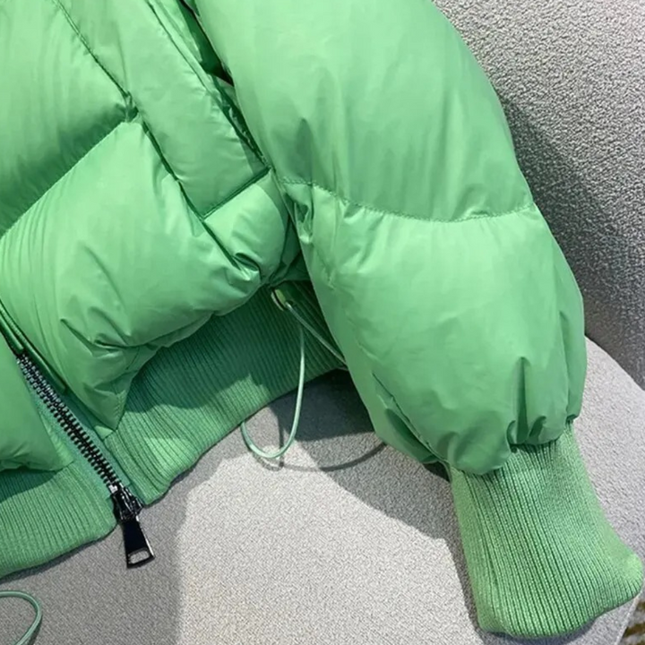 Groene gewatteerde jas met ritssluiting en geribde manchetten, detailopname. Modieuze winterjas, warme kleding, trendy damesmode.