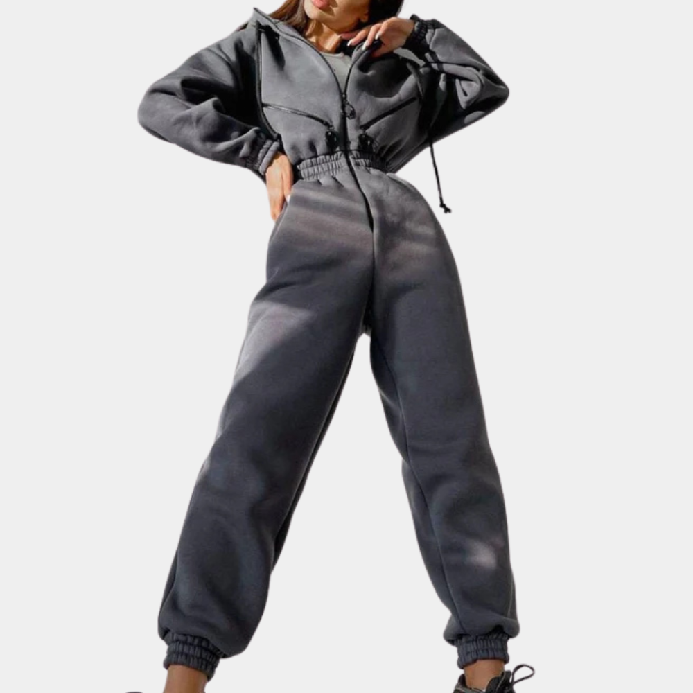 Vrouw in grijze jumpsuit met capuchon, elastische taille en boorden. Modieuze dameskleding, comfortabele pasvorm, casual stijl.