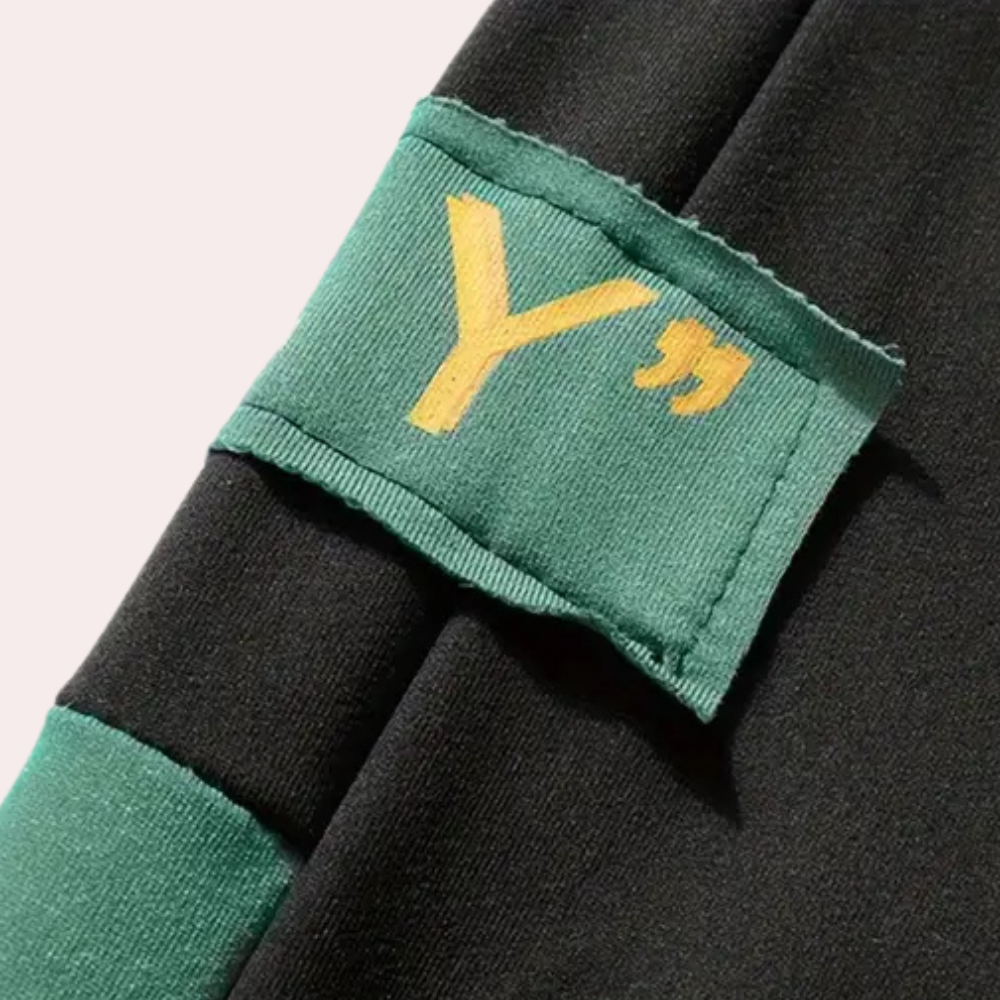 Zwarte hoodie met groene details en een geel "Y" logo op de mouw. Modieuze streetwear, unisex design, comfortabele pasvorm.