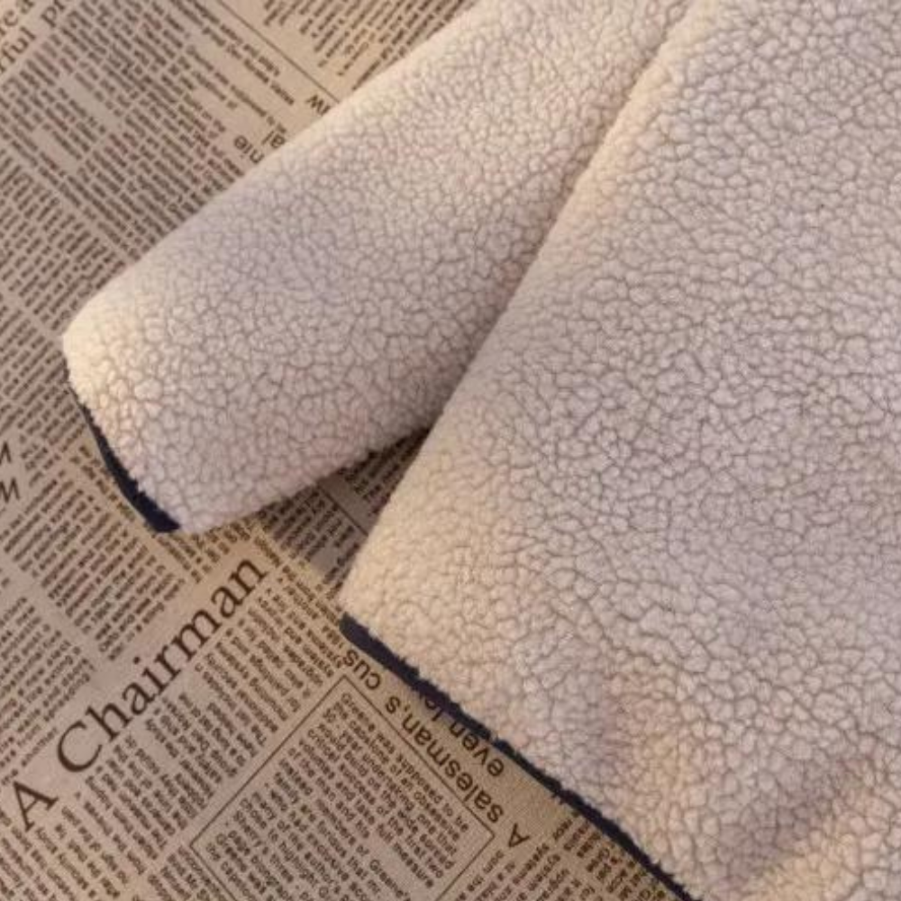 Witte sherpa fleece jas op krantenpapier, zachte textuur, warme winterkleding, trendy mode, comfortabele en stijlvolle buitenkleding.