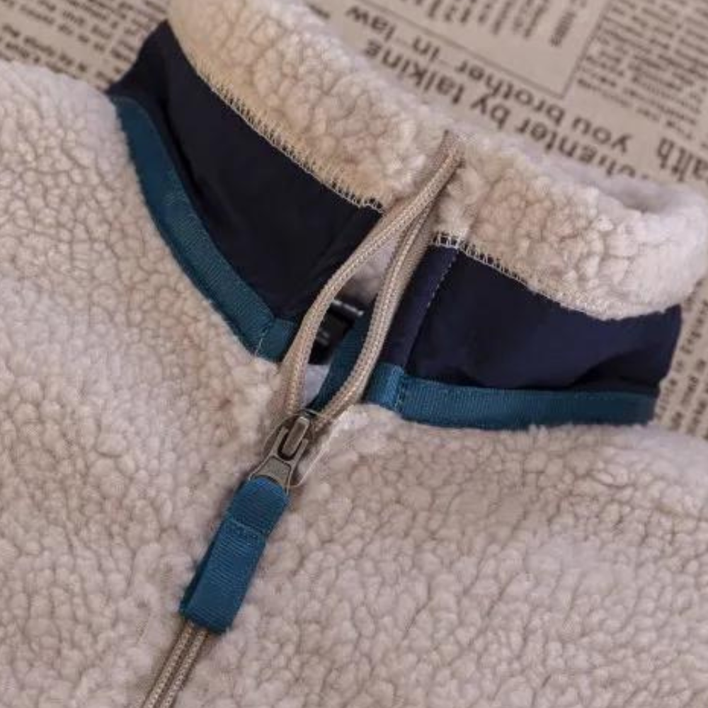 Witte fleece trui met blauwe kraag en ritssluiting, liggend op krant. Warme winterkleding, comfortabele stof, modieuze herenkleding.