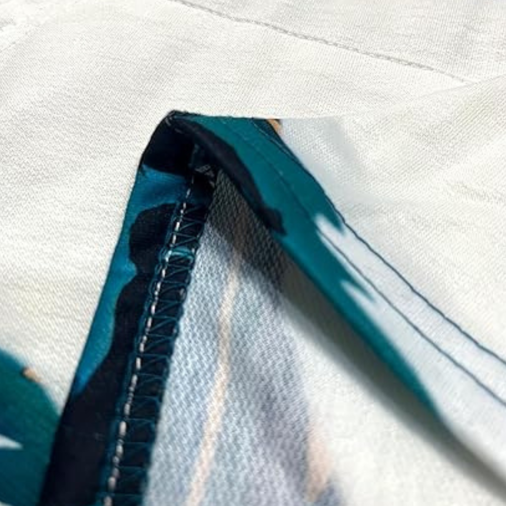 Close-up van een wit en blauw gestikt polyester tafelkleed met gedetailleerde zoom, ideaal voor moderne interieurdecoratie en tafelaankleding.