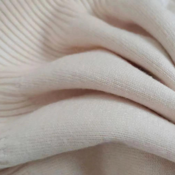 Crèmekleurige geribbelde stof close-up, zachte textuur, geschikt voor kleding en interieur, hoogwaardige textielmaterialen, modetrend 2023.