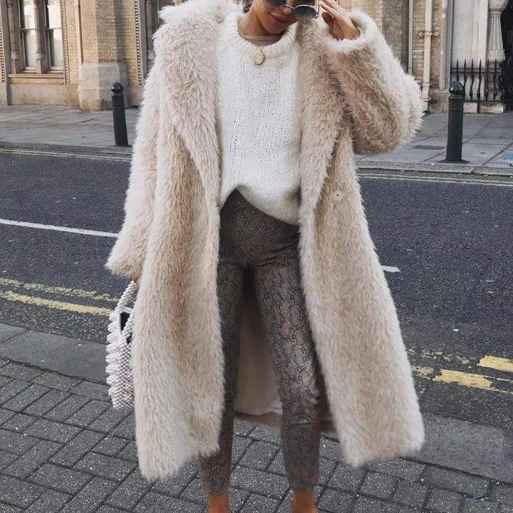 Vrouw in stijlvolle winteroutfit met lange beige teddyjas, witte trui en slangenprint broek, poseert op straat. Modieuze winterkleding, trendy look.