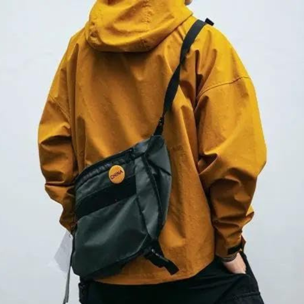 Oranje hoodie met zwarte schoudertas, casual streetwear stijl. Perfect voor modebewuste jongeren. Comfortabele en trendy outfit voor dagelijks gebruik.