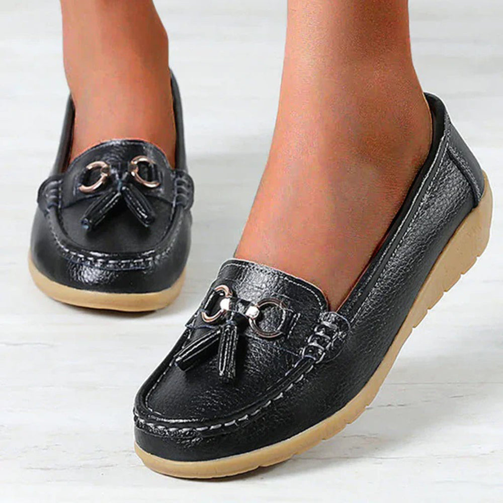 Zwarte leren instappers voor dames met decoratieve kwastjes en metalen details, comfortabele zool. Perfecte casual schoenen voor dagelijks gebruik.