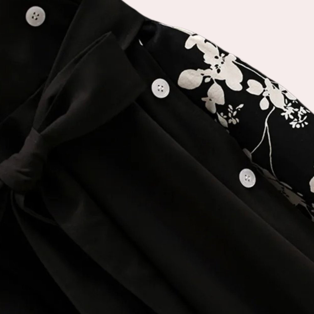 Zwart-witte blouse met bloemenprint en knoopdetails, elegante strik en witte knopen. Modieuze dameskleding, stijlvolle blouse voor elke gelegenheid.