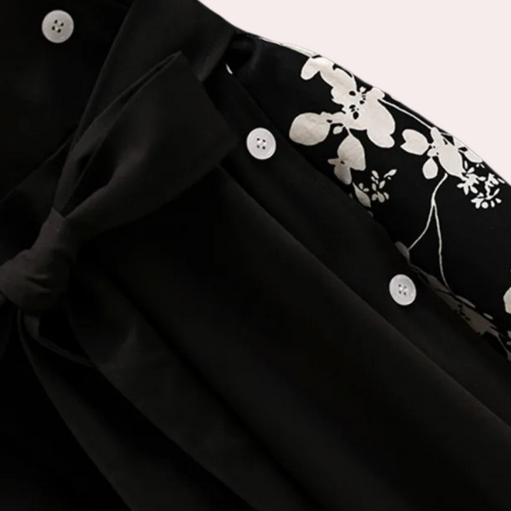 Zwart-witte blouse met bloemenprint en knoopdetails, elegante strik en witte knopen. Modieuze dameskleding, stijlvolle blouse voor elke gelegenheid.