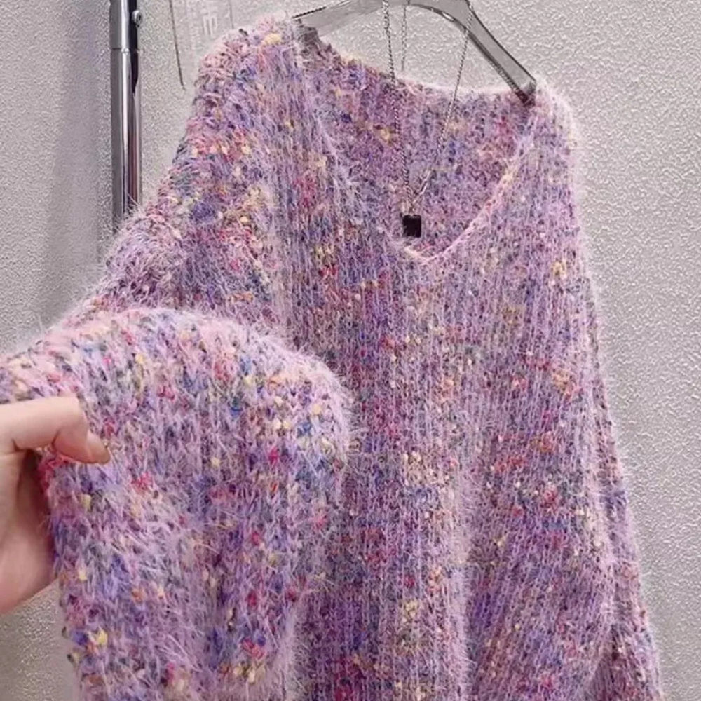Paarse gebreide trui met kleurrijke stippen, zachte textuur, hangend aan een kledinghanger. Perfect voor wintermode en casual outfits.