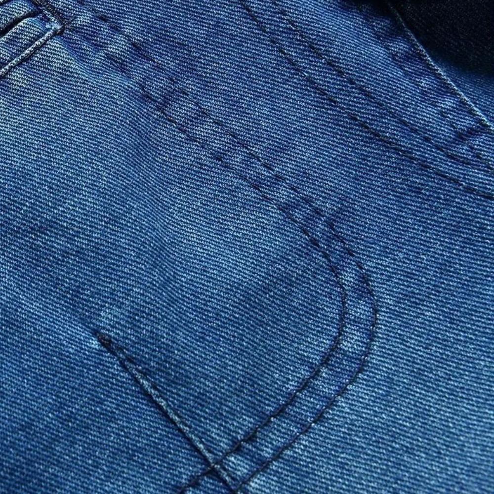Blauwe denimstof close-up met zichtbare stiksels en textuur, ideaal voor mode, jeans, en kledingontwerp. Hoogwaardige jeansstof detail.