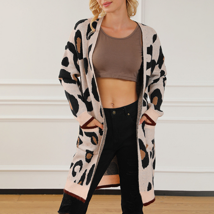 Vrouw draagt lange, beige cardigan met luipaardprint, gecombineerd met een bruine crop top en zwarte jeans. Modieuze dameskleding, herfststijl.