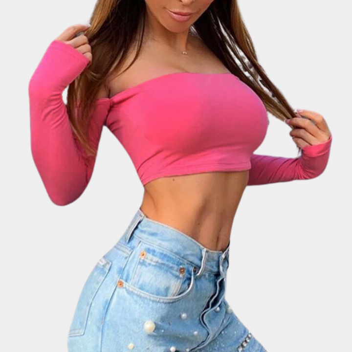 Vrouw in roze off-shoulder crop top en blauwe jeans met pareldetails. Modieuze dameskleding, trendy outfit, casual stijl.