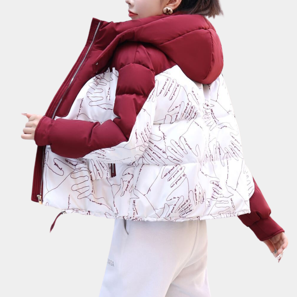 Rode en witte gewatteerde jas met handafdrukken, capuchon en ritssluiting, gedragen door model. Modieuze winterjas, trendy dameskleding.