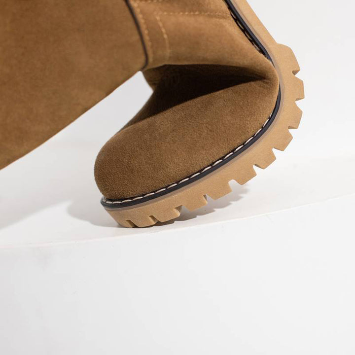 Bruine suède laars met dikke rubberen zool, close-up. Modieuze dameslaars, herfst- en winterstijl, comfortabele grip, trendy schoeisel.