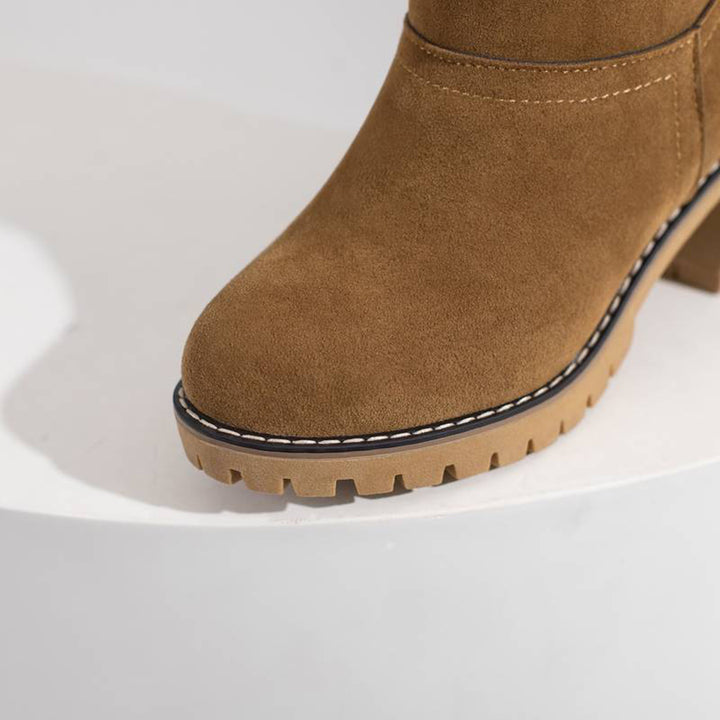 Bruine suède enkellaars met stevige rubberen zool en gestikte details, perfect voor herfstmode. Comfortabele en stijlvolle dameslaars.