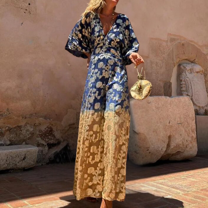 Stijlvolle damesjumpsuit met blauw-gouden bloemenprint, lange mouwen en vloeiende pasvorm, perfect voor zomerse gelegenheden en modieuze outfits.