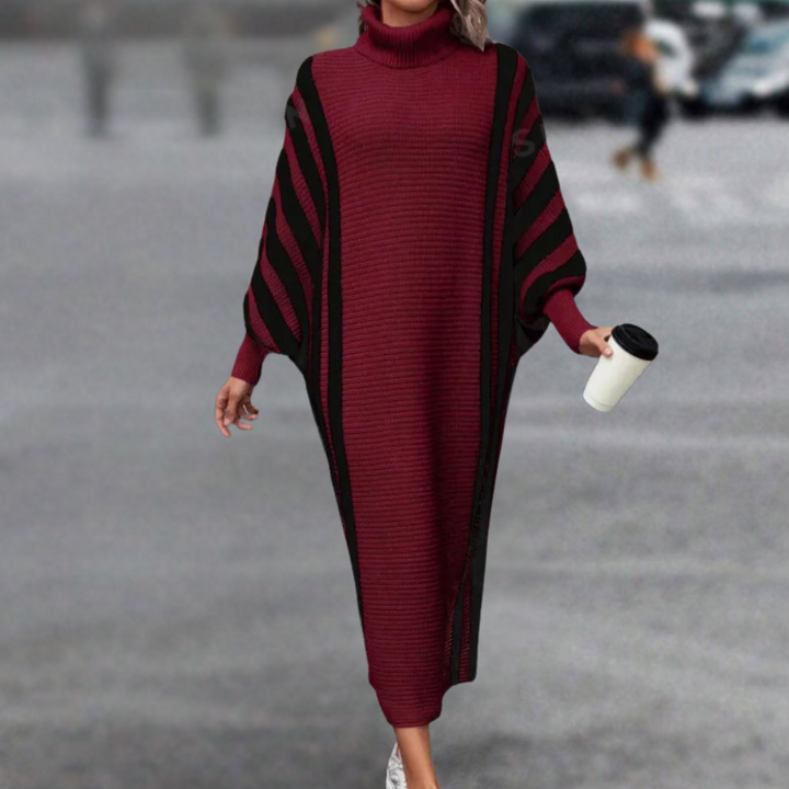 Vrouw in bordeauxrode, gestreepte trui-jurk met col, loopt buiten met koffiebeker. Modieuze herfstkleding, comfortabele damesmode.