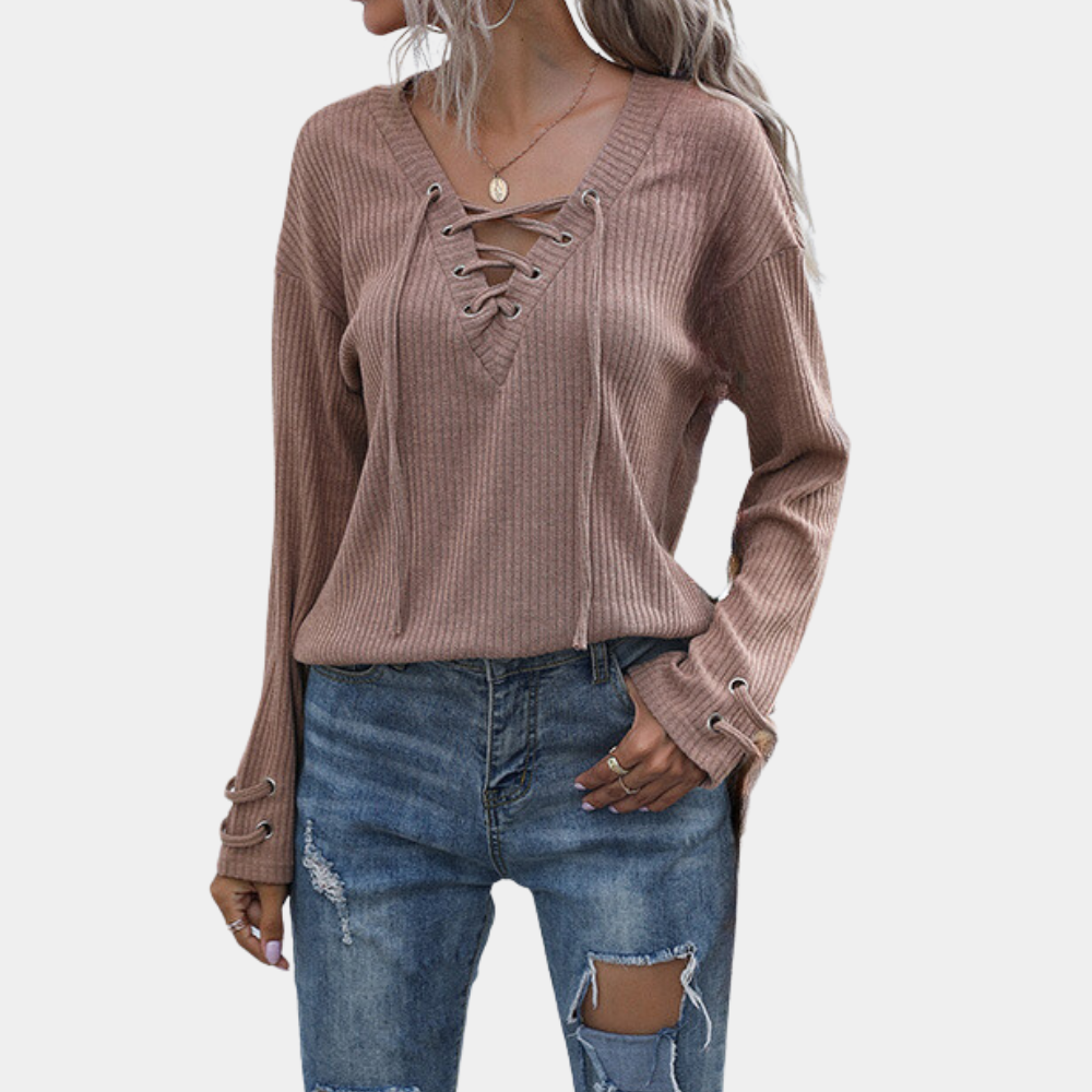 Vrouw draagt een bruin geribbelde trui met vetersluiting en blauwe gescheurde jeans. Modieuze dameskleding, casual herfstoutfit.