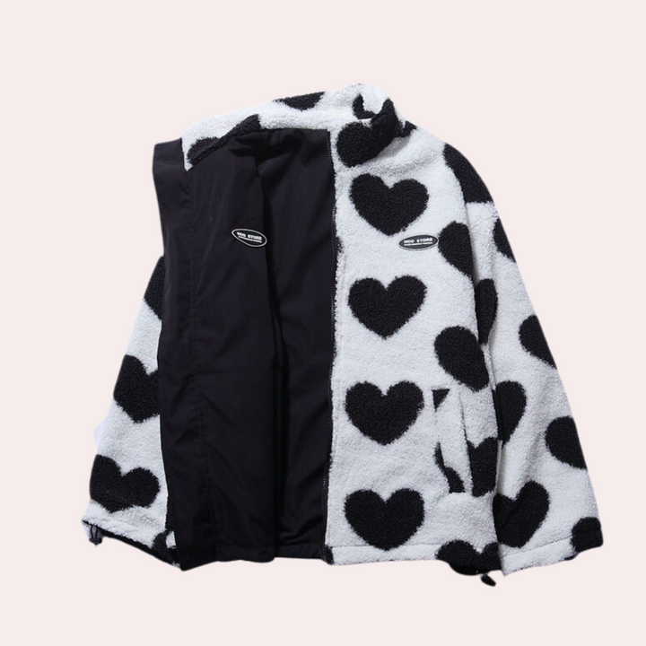 Zwart-witte fleece jas met hartjespatroon, open rits, en binnenvoering. Trendy damesmode, warme winterjas, casual stijl.