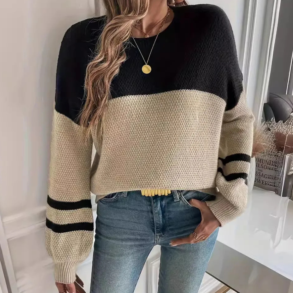 Vrouw draagt stijlvolle zwart-beige trui met strepen, gecombineerd met blauwe jeans. Modieuze herfstkleding, casual damesoutfit, trendy look.