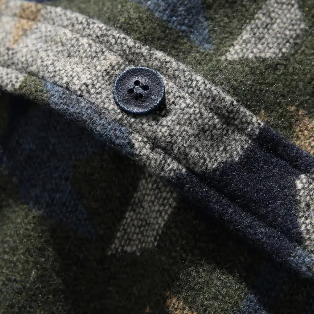Close-up van een groene camouflage jas met een zwarte knoop, gemaakt van wol. Ideaal voor outdoor kleding, herfstmode, en militaire stijl.