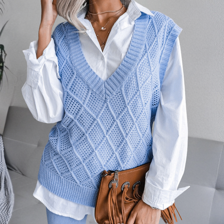 Vrouw in blauwe gebreide spencer over witte blouse, met bruine leren tas. Modieuze dameskleding, herfstoutfit, casual stijl.
