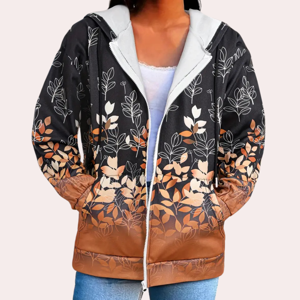 Vrouw draagt zwarte hoodie met witte en bruine bladerenprint, ritssluiting en capuchon. Modieuze herfstkleding, casual stijl, comfortabele pasvorm.