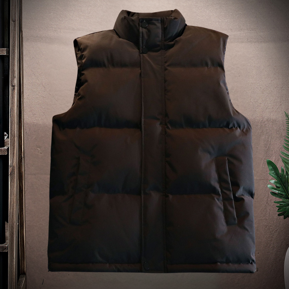 Donkerbruine gewatteerde bodywarmer zonder mouwen, opgehangen tegen een grijze achtergrond. Ideaal voor wintermode en outdooractiviteiten.