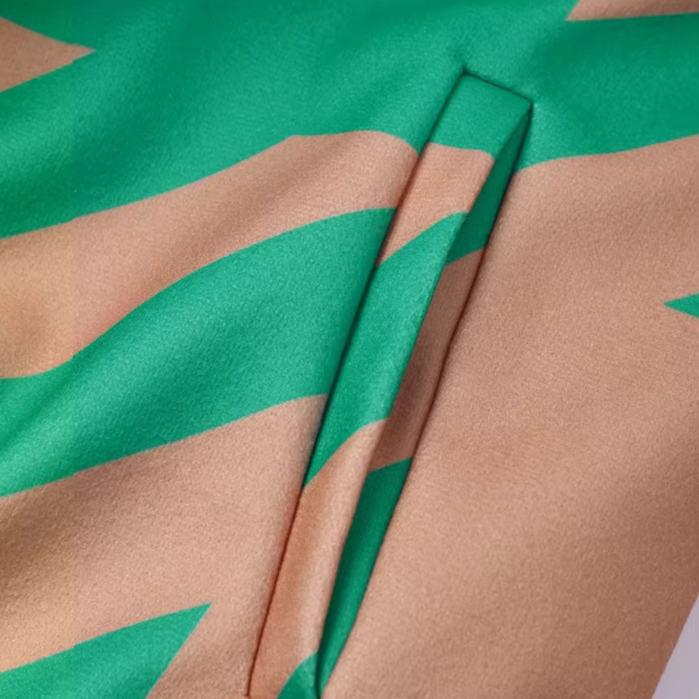 Groen en beige gestreepte satijnen stof met een subtiele glans, close-up van een naad. Luxe textiel, modeontwerp, hoogwaardige materialen.