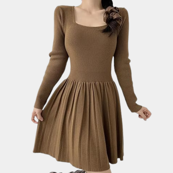 Bruine gebreide jurk met lange mouwen en geplooide rok, vierkante halslijn en bloemdetail op de schouder. Elegante damesmode, herfstkleding.